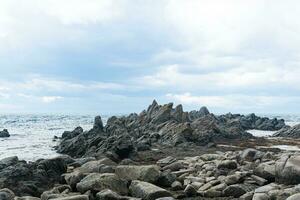 agudo dentado basalto rocas en el mar costa, capa stolbchaty en kunashir isla foto