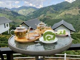 tea from glass teapot on wooden serving tray, hands pouring tea from teapot, Cropped shot of pouring tea in traditional chinese tea ware, piece of white cake photo