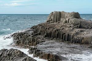 rocky seashore formed by columnar basalt against the stormy sea, coastal landscape of the Kuril Islands photo