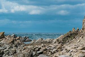 sharp jagged basalt rocks on the sea coast photo