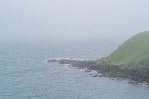 high deserted grassy promontory over a cold foggy sea photo