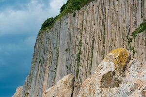 alto costero acantilado formado por Roca columnas, capa stolbchaty en el isla de kunashir foto