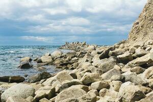 sharp jagged basalt rocks on the sea coast, Cape Stolbchaty on Kunashir Island photo