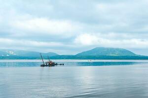 shipwreck against the backdrop of a sea bay with foggy mountains in the background photo