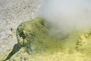 smoking vent of a solfatara in a fumarole field on a slope of the volcano photo