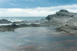 coastal cliffs formed by columnar basalt at low tide photo