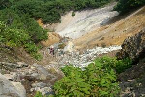 tourist photographs a geothermal mineralized stream on the slope of the Mendeleev volcano, Kunashir island photo