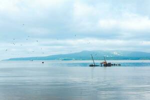shipwreck against the backdrop of a sea bay with foggy mountains in the background photo
