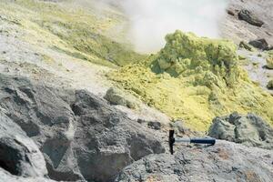 geological hammer in the rock against the backdrop of an steaming fumarole on the slope of a volcano photo