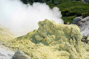 smoking solfatara among sulfur deposits on the slope of the volcano photo