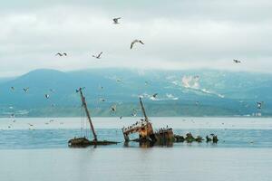 shipwreck against the backdrop of a sea bay with foggy mountains in the background photo