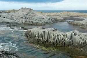 coastal cliffs formed by columnar basalt at low tide photo