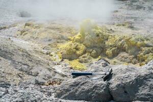 geological hammer on the rock against the backdrop of an steaming fumarole on the slope of a volcano photo