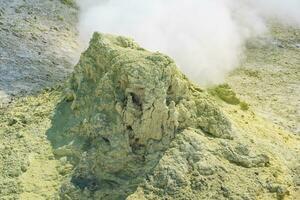 amarillo cono de cristalizado azufre alrededor un de fumar solfatara en el Pendiente de un volcán foto