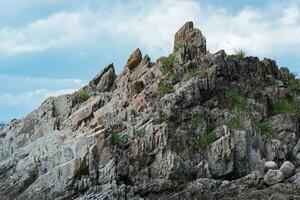 top of a steep rocky cliff of volcanic basalt against the sky photo