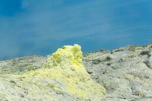 sulfur deposits around a solfatara in a fumarole field against a blue sky photo