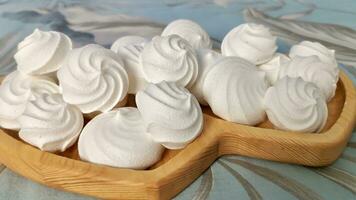 Close-up of freshly cooked white meringue laid out on a wooden plate photo