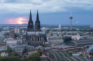 Dramatic storm clouds over Cologne Cathedral and Hohenzollern Bridge in the sunset photo