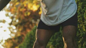 Athletic runner doing stretching exercise, preparing for running in the nature with the city in background. Healthy lifestyle video