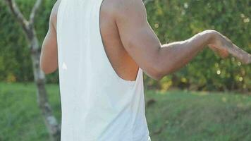 Athletic runner doing stretching exercise, preparing for running in the nature with the city in background. Healthy lifestyle video