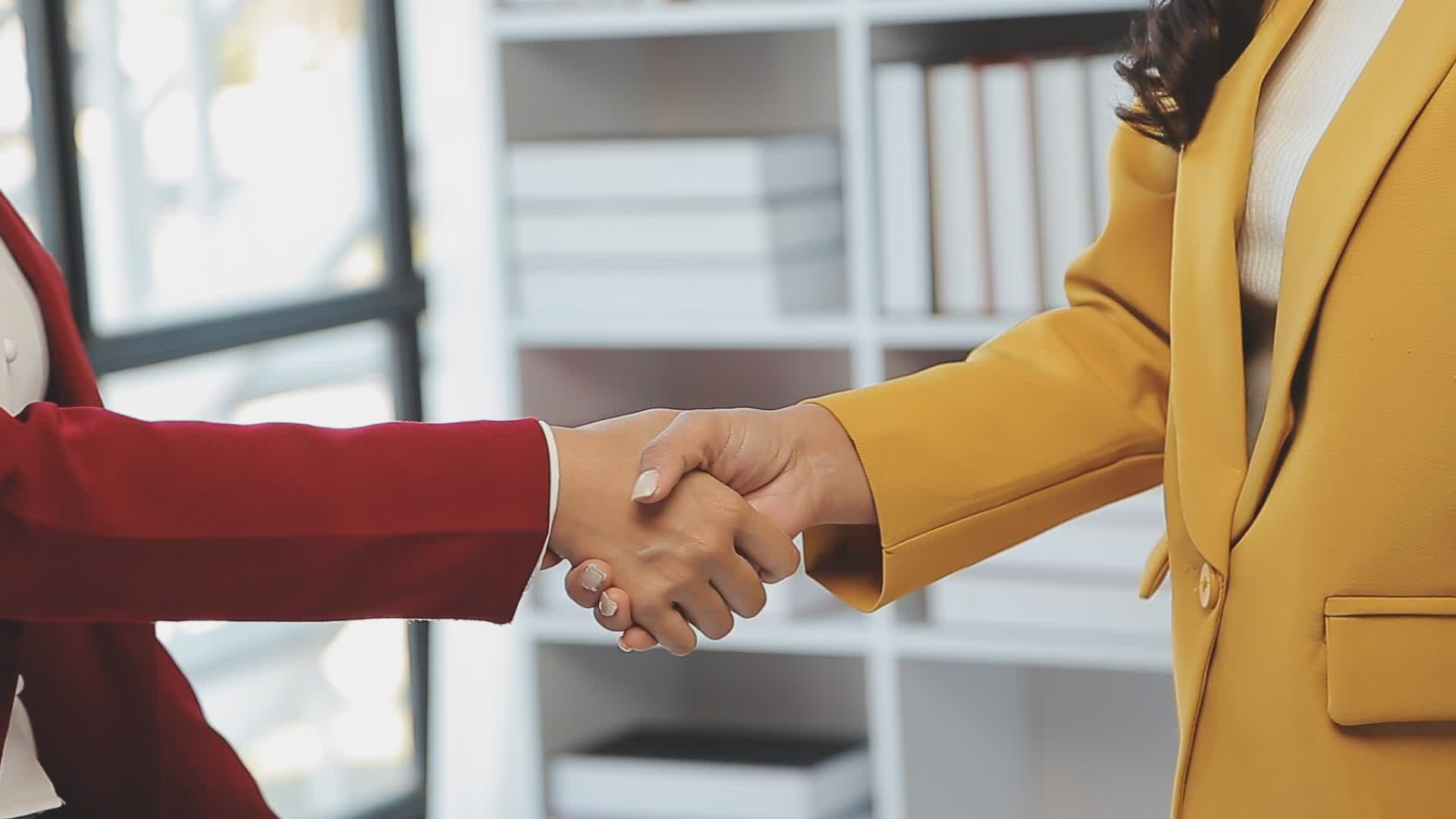 Real estate broker agent and customer shaking hands after signing