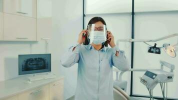 Dental Health Professional Preparing for Appointment, Dental worker adjusting face shield and mask before patient interaction video