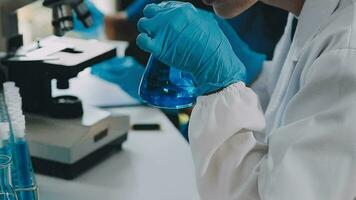 Young scientists conducting research investigations in a medical laboratory, a researcher in the foreground is using a microscope video