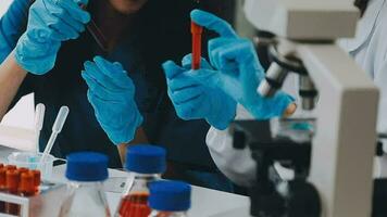 Young scientists conducting research investigations in a medical laboratory, a researcher in the foreground is using a microscope video