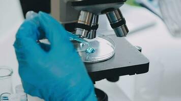 Young scientists conducting research investigations in a medical laboratory, a researcher in the foreground is using a microscope video