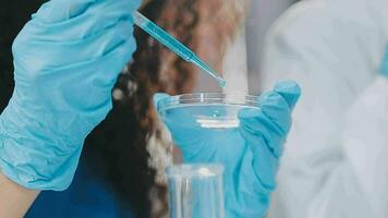 Young scientists conducting research investigations in a medical laboratory, a researcher in the foreground is using a microscope video