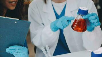 Young scientists conducting research investigations in a medical laboratory, a researcher in the foreground is using a microscope video