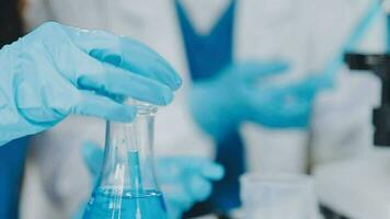 Young scientists conducting research investigations in a medical laboratory, a researcher in the foreground is using a microscope video