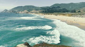 ver desde el acantilado en un grande arenoso playa de el Pacífico Oceano en California. grande olas ven a el costa. el increíble naturaleza de el línea costera de el Pacífico océano. video