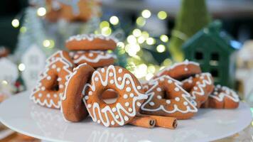 Freshly baked Christmas gingerbread cookies are decorated with confectionery glaze on a rotating surface in a New Year's decor. A close-up of a spinning gingerbread cookie video