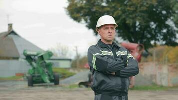 Foreman Overlooking Grain Silos. Serious foreman with arms crossed in front of grain storage silos video