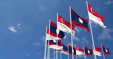 Laos et Singapour drapeaux agitant ensemble dans le ciel, sans couture boucle dans vent, espace sur la gauche côté pour conception ou information, 3d le rendu video