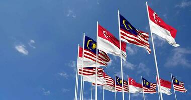Malaysia e Singapore bandiere agitando insieme nel il cielo, senza soluzione di continuità ciclo continuo nel vento, spazio su sinistra lato per design o informazione, 3d interpretazione video