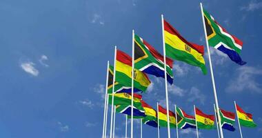 Bolivie et Sud Afrique drapeaux agitant ensemble dans le ciel, sans couture boucle dans vent, espace sur la gauche côté pour conception ou information, 3d le rendu video