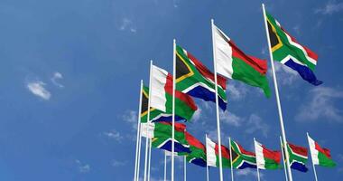 Madagaskar und Süd Afrika Flaggen winken zusammen im das Himmel, nahtlos Schleife im Wind, Raum auf links Seite zum Design oder Information, 3d Rendern video