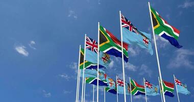 fiji e Sud Africa bandiere agitando insieme nel il cielo, senza soluzione di continuità ciclo continuo nel vento, spazio su sinistra lato per design o informazione, 3d interpretazione video