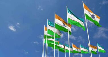 Uzbekistán y India bandera ondulación juntos en el cielo, sin costura lazo en viento, espacio en izquierda lado para diseño o información, 3d representación video