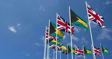 Bahamas och förenad rike flaggor vinka tillsammans i de himmel, sömlös slinga i vind, Plats på vänster sida för design eller information, 3d tolkning video