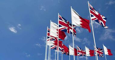 bahrain och förenad rike flaggor vinka tillsammans i de himmel, sömlös slinga i vind, Plats på vänster sida för design eller information, 3d tolkning video