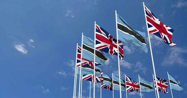 botswana en Verenigde koninkrijk vlaggen golvend samen in de lucht, naadloos lus in wind, ruimte Aan links kant voor ontwerp of informatie, 3d renderen video