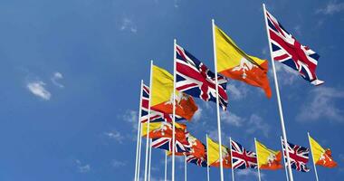 Bhutan and United Kingdom Flags Waving Together in the Sky, Seamless Loop in Wind, Space on Left Side for Design or Information, 3D Rendering video