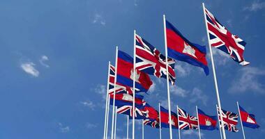 Cambodge et uni Royaume drapeaux agitant ensemble dans le ciel, sans couture boucle dans vent, espace sur la gauche côté pour conception ou information, 3d le rendu video