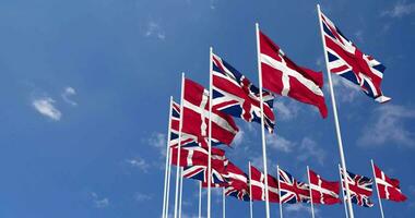 Danemark et uni Royaume drapeaux agitant ensemble dans le ciel, sans couture boucle dans vent, espace sur la gauche côté pour conception ou information, 3d le rendu video