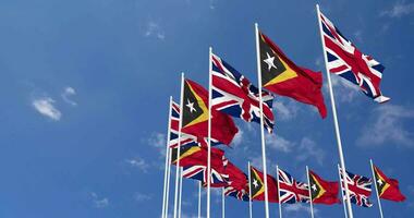 East Timor and United Kingdom Flags Waving Together in the Sky, Seamless Loop in Wind, Space on Left Side for Design or Information, 3D Rendering video