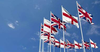 Angleterre et uni Royaume drapeaux agitant ensemble dans le ciel, sans couture boucle dans vent, espace sur la gauche côté pour conception ou information, 3d le rendu video