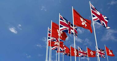 Hong kong et uni Royaume drapeaux agitant ensemble dans le ciel, sans couture boucle dans vent, espace sur la gauche côté pour conception ou information, 3d le rendu video